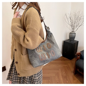 Détail du grand lettrage WIO WIO en cuir sur le sac à main en toile délavée et élégante