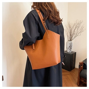 Grande borsa tote marrone arancio in pelle testurizzata indossata da una modella in un interno