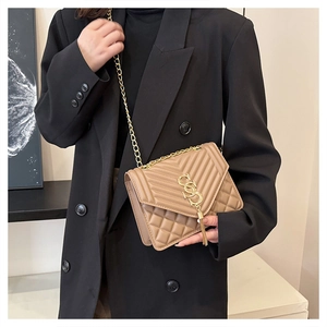 Detail of beige leather crossbody bag with V-shaped quilting and gold metal tassel