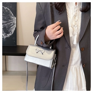 Mini sac argenté métallisé avec nœud en métal et bandoulière amovible sur un mannequin