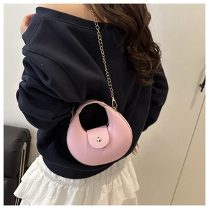 Pink crescent mini handbag with gold chain strap and top handle shown on model