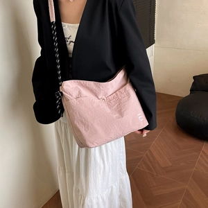 Pink pleated nylon shoulder bag with woven strap and logo detail for casual use