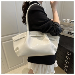 Chic white glossy tote bag with unique pleated texture and slim shoulder straps on a model