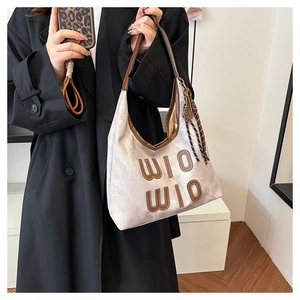 Gros plan du sac bandoulière en toile avec finitions en cuir marron et pompon
