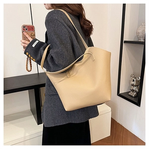 Dettaglio della borsa tote beige con trama in pelle opaca e sottili spalline morbide