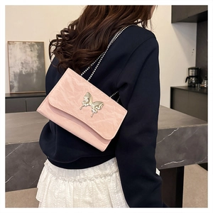 Detail of pink ruched leather shoulder bag with silver butterfly buckle and chain strap