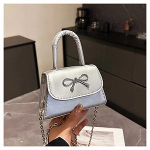 Close-up of mini silver handbag with metallic bow and fine chain strap detail