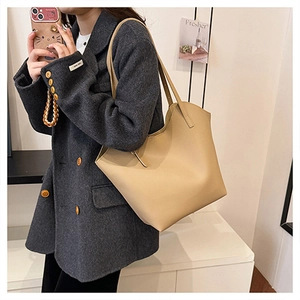 Dettaglio della trama in pelle martellata beige della borsa tote indossata da una modella