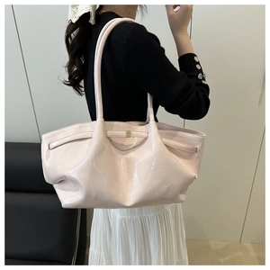 Detail of pink glossy patent leather tote bag with pleated design worn on shoulder