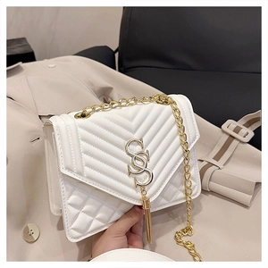 Detail of white quilted crossbody bag with golden chain and tassel accent