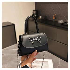 Detail of black PU leather mini handbag featuring silver bow and round chain strap