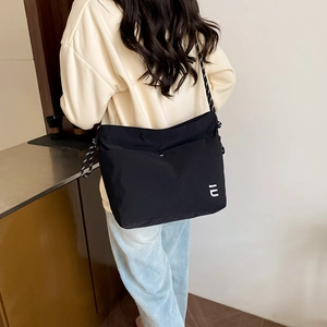Grand sac cabas noir en nylon avec large bandoulière porté par un mannequin