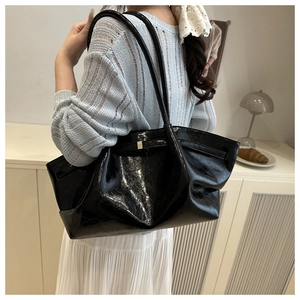 Close-up of black glossy tote bag with crinkle texture and gold buckle detail