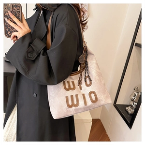 Détail du sac cabas en toile grise avec patchs en cuir WIO et breloque de tennis