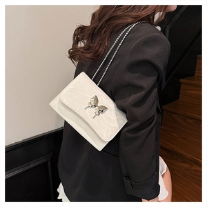 Detailed close-up of white pleated leather bag with silver butterfly buckle and chain