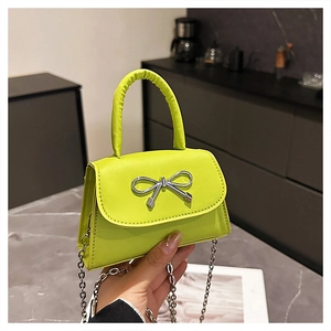 Detail of neon green mini bag with silver bow clasp and metallic chain strap