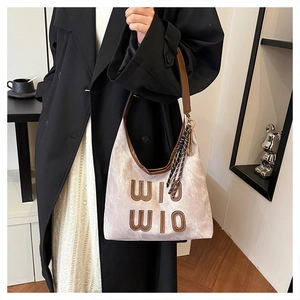 Détail du sac hobo avec texture marbre, garniture en cuir brun et foulard décoratif