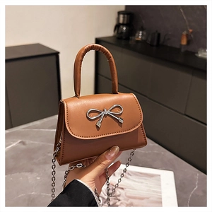 Close-up of brown mini crossbody bag with silver bow detail and metal chain strap