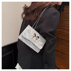 Detail shot of silver wrinkled texture crossbody bag with metal butterfly buckle on model