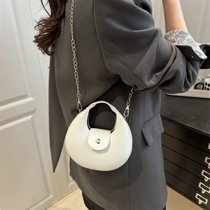 Minimalist white crescent shoulder bag with gold hardware worn by model in a modern room