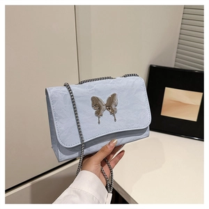 Close-up of light blue wrinkled fabric shoulder bag with silver fluid butterfly detail
