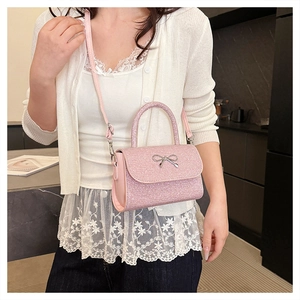 Pink glitter mini crossbody bag with silver metal bow detail shown on a model