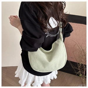 Detail van de lichtgroene corduroy hobo tas gedragen door model in een binnenruimte