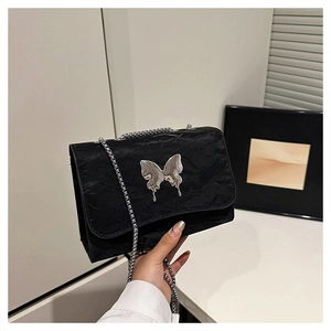 Detail of black pleated crossbody bag with a metallic silver butterfly buckle accessory