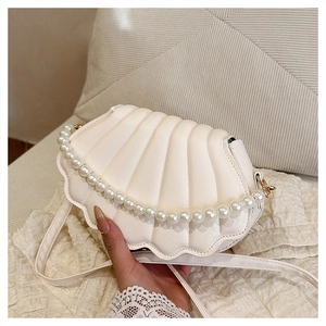 Detailed view of beige shell-shaped bag with pearl handle and matte PU leather texture