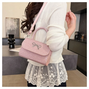 Detail of pink sequin crossbody bag with silver metal bow and matching leather strap