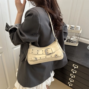 Elegante borsa baguette in pelle crema con cinturini a fibbia e occhielli metallici sulla modella