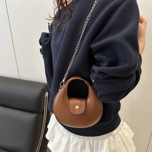 Women's dark brown half-moon mini leather bag with gold chain strap worn by model