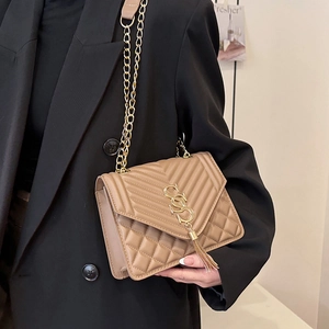 Elegant beige quilted leather crossbody bag with gold chain and tassel on model