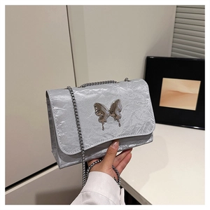 Detail of silver pleated shoulder bag featuring a liquid metal butterfly buckle and chain