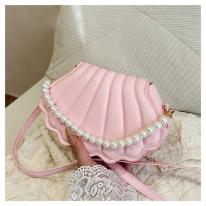 Detailed macro view of pink shell-shaped crossbody bag with pearl handle and leather texture