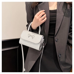 Detailed view of a silver sequined handbag with a metallic bow detail and crossbody strap