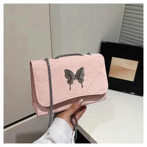 Close-up of pink wrinkled texture shoulder bag with liquid silver butterfly charm