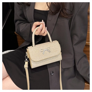 Close-up of champagne gold glitter crossbody bag with silver metal bow detail