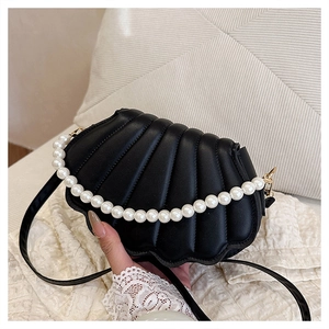 Detail of shell-shaped crossbody bag featuring pearl handle and quilted leather texture