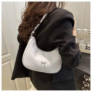 Close-up of white crescent shoulder bag featuring a silver bow and glossy finish