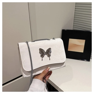 Detail of white leather shoulder bag featuring metallic silver butterfly buckle and chain