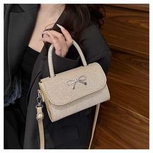 Close-up of champagne gold sequined handbag with silver metal bow and top handle