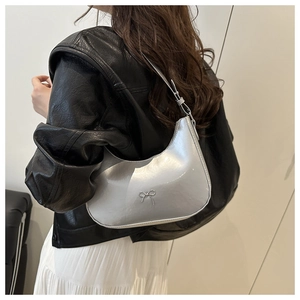Detail of silver crescent shoulder bag with metallic finish and delicate bow decoration