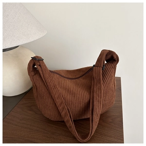 Detail van de bruine corduroy tas met verticale ribbeltextuur en een brede schouderriem