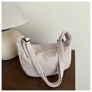 Detail van beige corduroy halve maan tas met weergave van textuur en gesp van riem