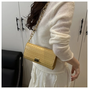 Detail of yellow crocodile pattern baguette bag with chunky gold chain strap and metal clasp