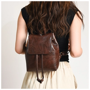 Detail of vintage brown leather backpack showing drawstring closure and adjustable straps