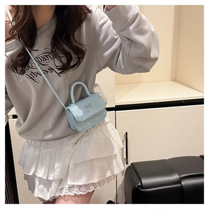 Detail of light blue mini handbag with metal bow and white polka dot pattern
