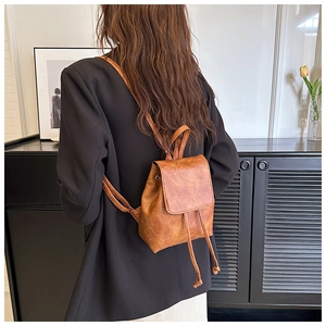 Brown vintage style mini leather backpack worn over a black blazer in a chic interior