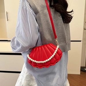 Elegant red shell crossbody bag with pleated texture and pearl chain strap on model
